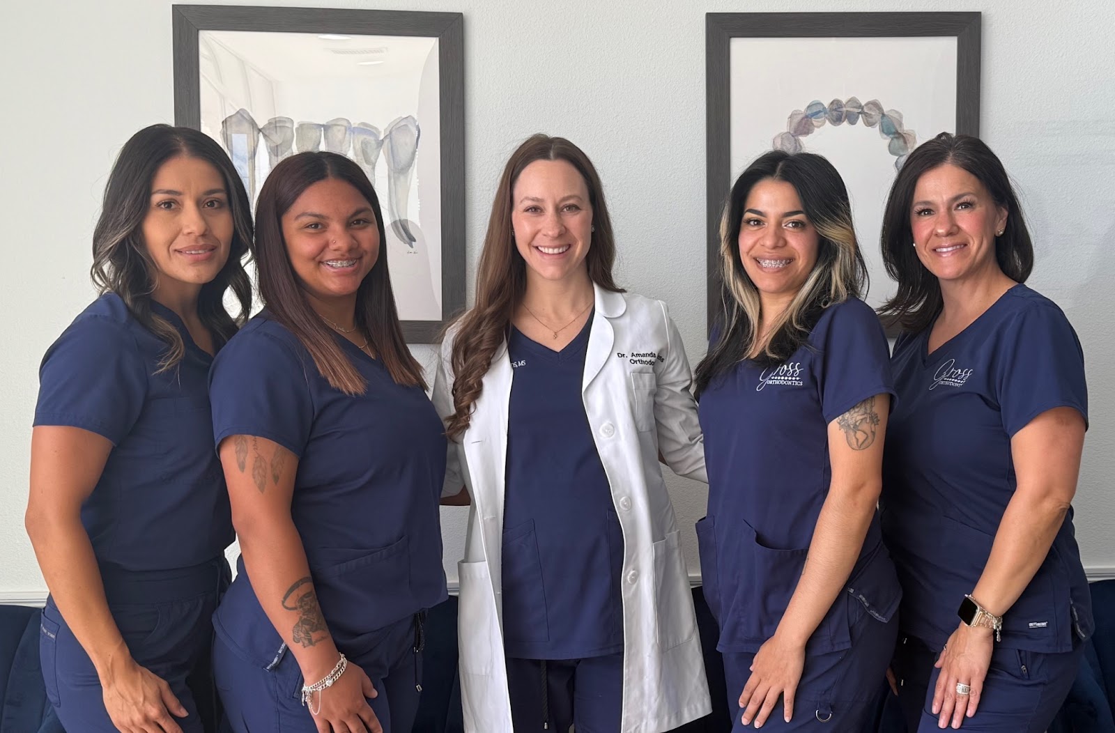 Dr. Amanda Gross and orthodontic team in navy scrubs, smiling in front of dental art, promoting airway-centered orthodontics at Gross Orthodontics in El Paso.